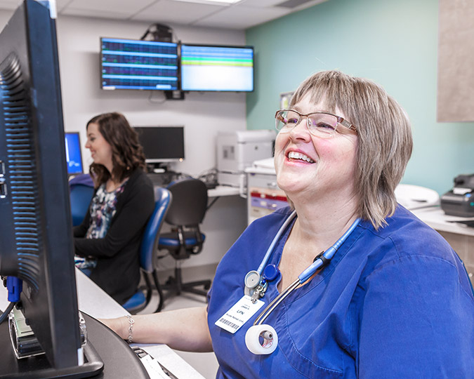 A female nurse smiling while looking at her computer screen