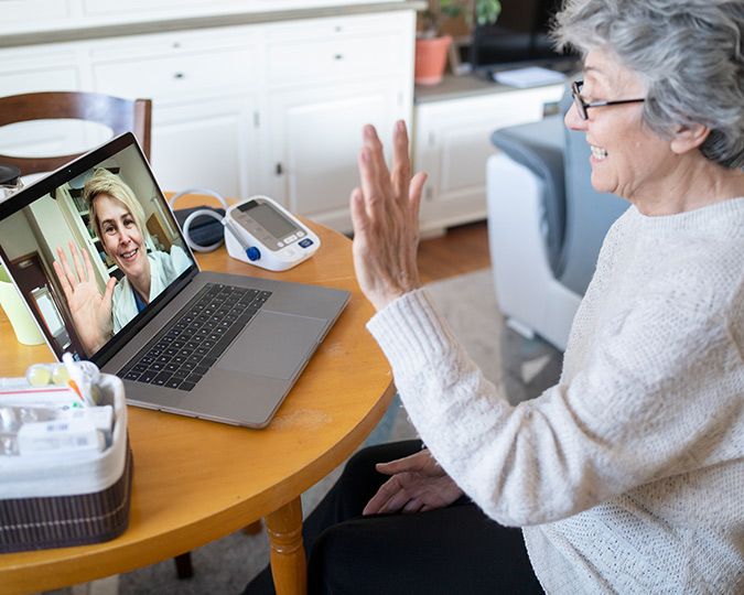 An elderly woman talking with a nurse over the computer via a virtual appointment