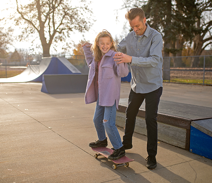 a little girl skateboarding with her dad