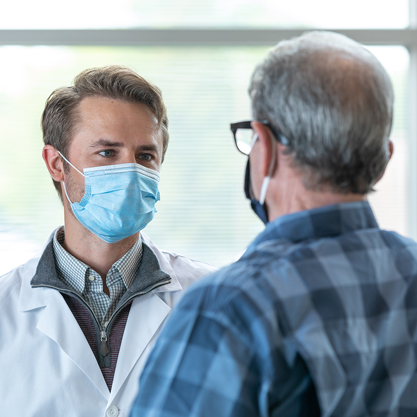 Dr. Seth Maliske wearing a mask talking with a patient