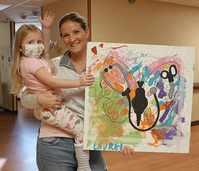Child being held with picture they painted