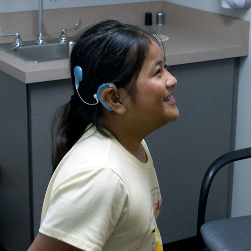 A young girl with a cochlear implant smiling