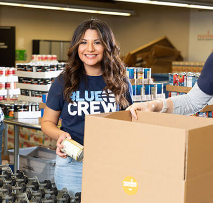 Marketing Blue Crew woman putting cans in a box