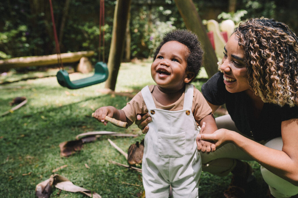 Mom and her cute little baby having fun in the playground, in the garden