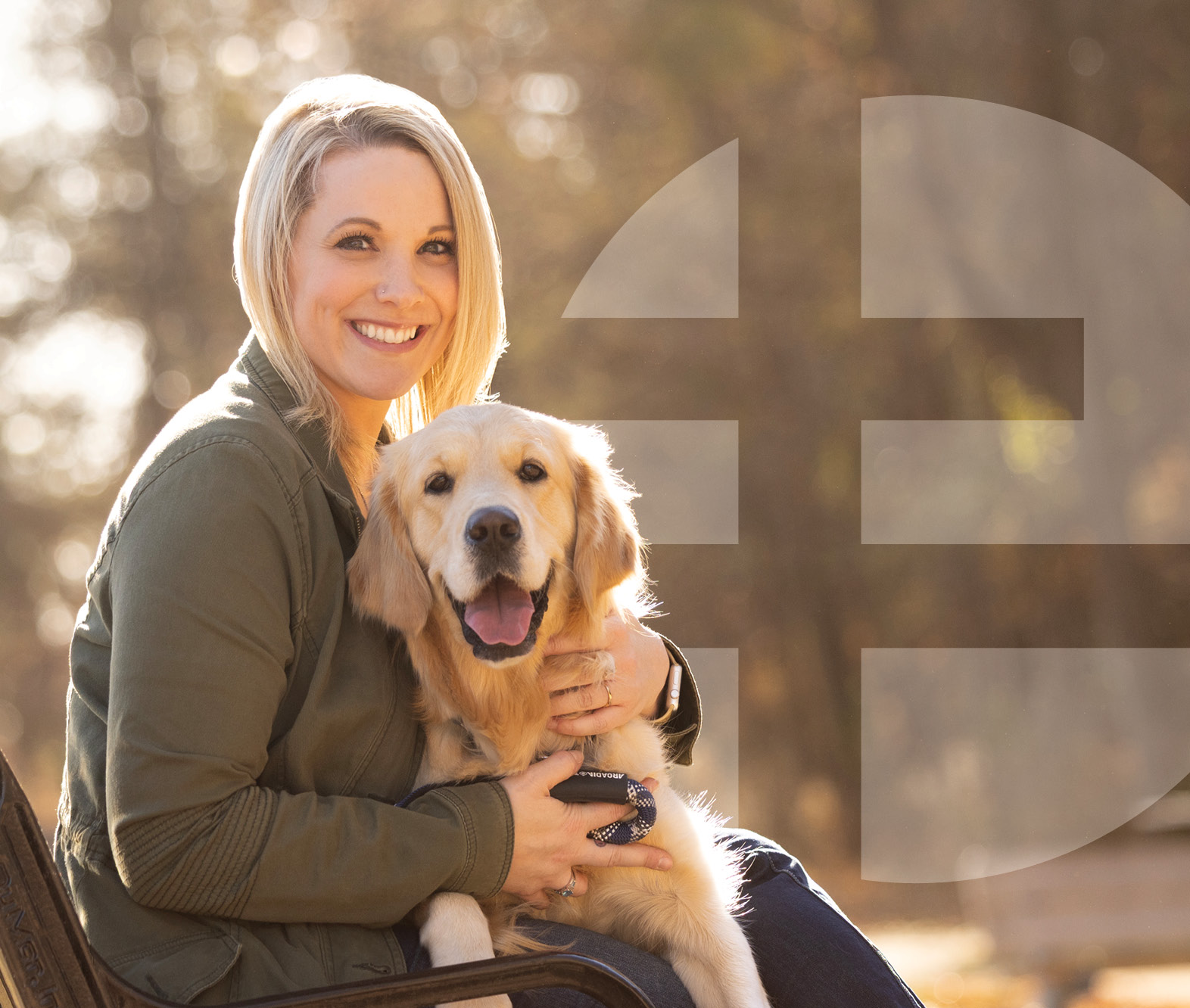 Woman sitting outside with a dog on her lap.