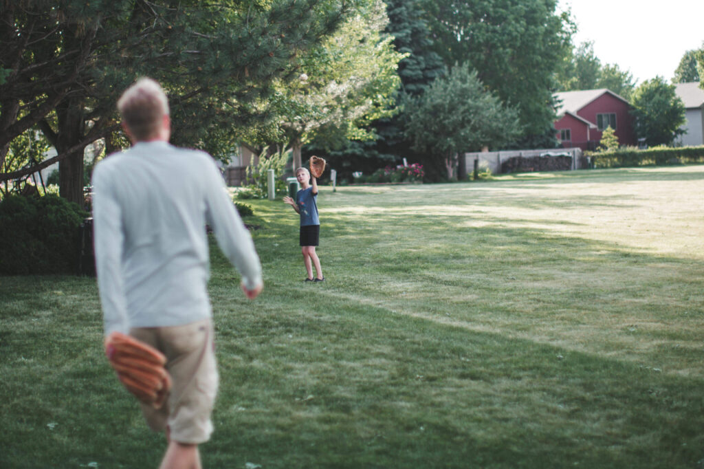Son playing catch outside with his dad.